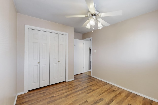 unfurnished bedroom featuring ceiling fan, a closet, wood finished floors, and baseboards