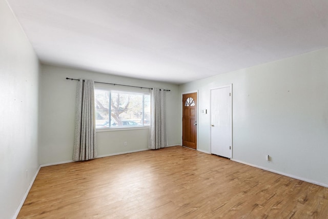 spare room featuring baseboards and light wood-style floors