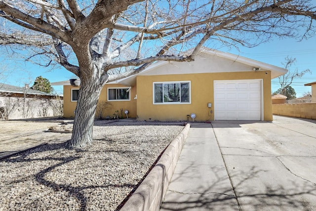 ranch-style home with fence, driveway, an attached garage, and stucco siding