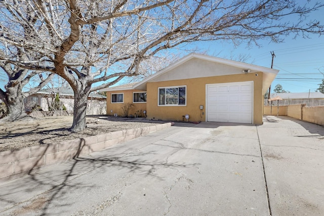 view of side of home featuring a garage, concrete driveway, fence, and stucco siding