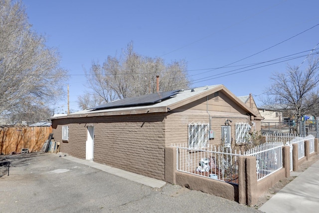 view of home's exterior with roof mounted solar panels and fence