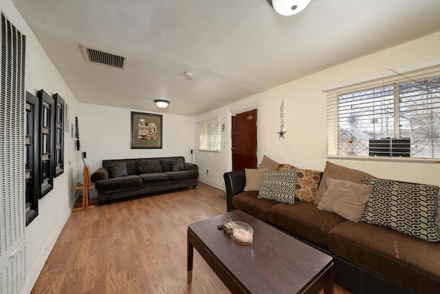 living area featuring visible vents, baseboards, and wood finished floors