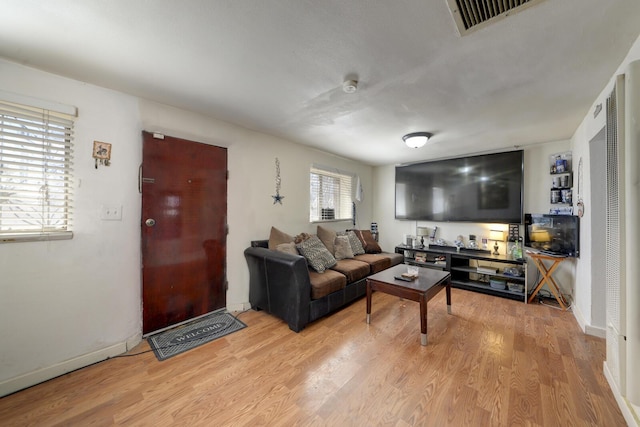 living area featuring light wood finished floors, visible vents, and baseboards