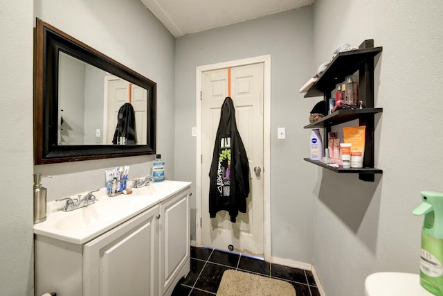 half bath with toilet, tile patterned flooring, baseboards, and vanity