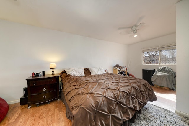 bedroom with a ceiling fan, light wood-style flooring, and baseboards