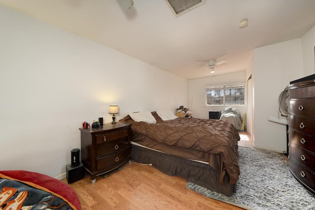 bedroom featuring light wood finished floors, baseboards, visible vents, and a ceiling fan