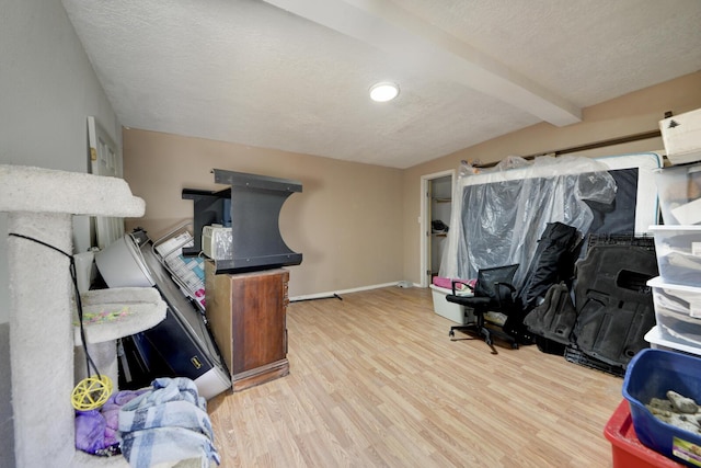 home office with beamed ceiling, a textured ceiling, baseboards, and wood finished floors