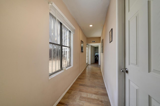 hall featuring light wood-type flooring, visible vents, and baseboards