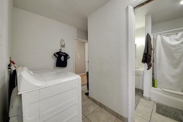 clothes washing area with laundry area, baseboards, a textured ceiling, and light tile patterned flooring