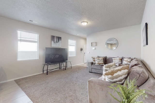 living area featuring visible vents, a textured ceiling, and baseboards