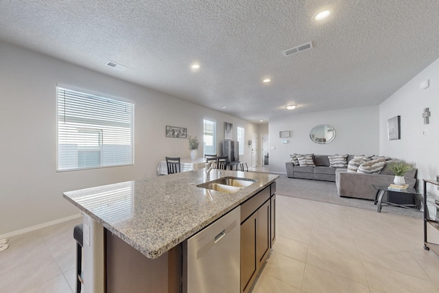 kitchen with a sink, visible vents, stainless steel dishwasher, and an island with sink