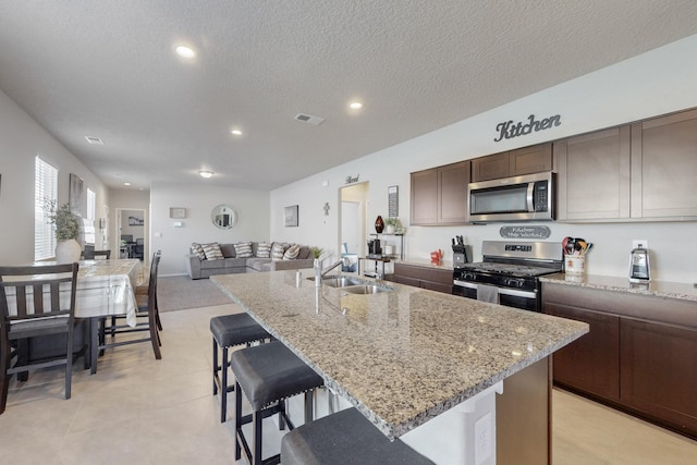 kitchen with stainless steel appliances, visible vents, a sink, and light stone countertops