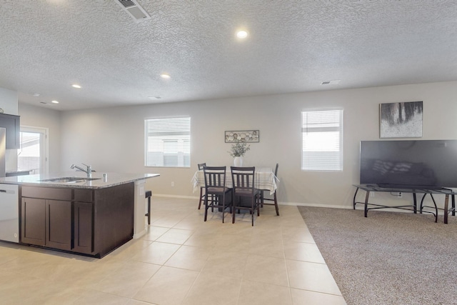 kitchen with light tile patterned floors, dishwashing machine, plenty of natural light, and a sink