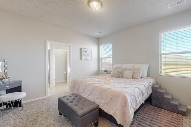 carpeted bedroom with visible vents, a textured ceiling, and baseboards