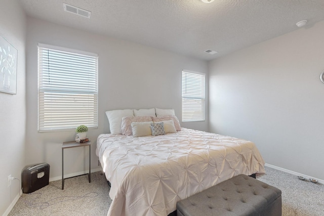 bedroom with baseboards, a textured ceiling, and light colored carpet