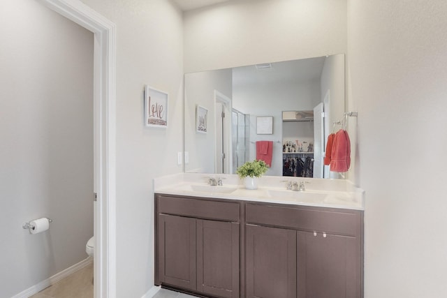 full bath with a sink, a spacious closet, toilet, and double vanity