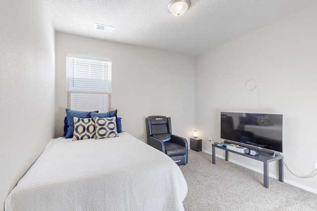 bedroom with carpet floors, visible vents, baseboards, and a textured ceiling