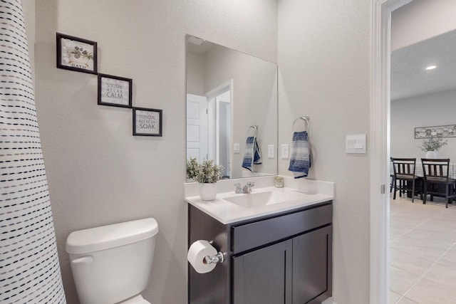 half bath featuring vanity, toilet, and tile patterned floors