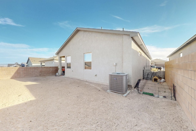 rear view of house featuring central air condition unit, a fenced backyard, and stucco siding