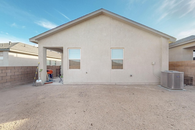 rear view of property featuring a patio area, fence, central AC, and stucco siding