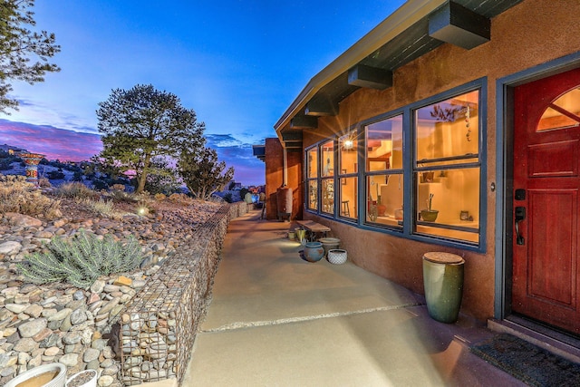 exterior entry at dusk featuring stucco siding