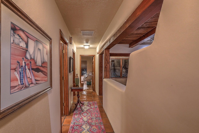 hallway featuring a textured ceiling, visible vents, and tile patterned floors