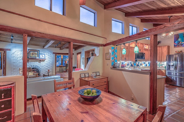 tiled dining room with wood ceiling, a fireplace, beamed ceiling, and a towering ceiling