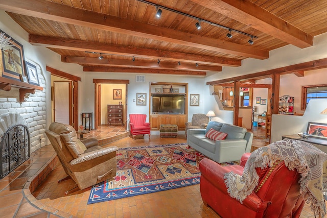 living area with brick floor, beam ceiling, visible vents, a stone fireplace, and wooden ceiling