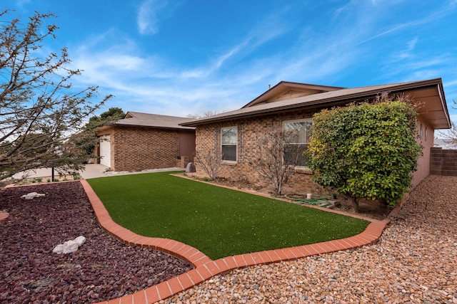 rear view of house featuring brick siding, a yard, and fence