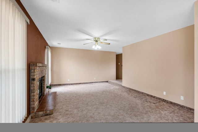 unfurnished living room with a ceiling fan, a brick fireplace, carpet floors, and baseboards