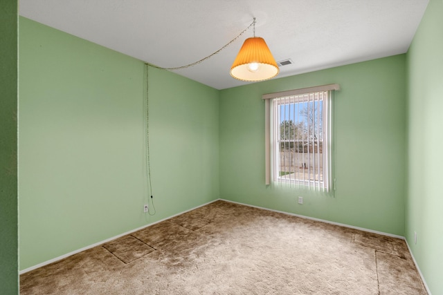 carpeted spare room featuring baseboards and visible vents