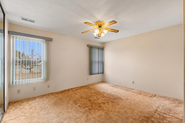 unfurnished room with a ceiling fan, visible vents, carpet floors, and a textured ceiling