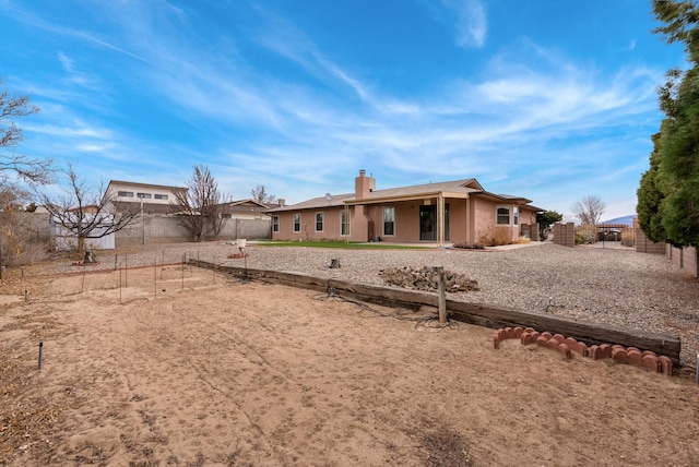 back of property with fence, a chimney, and stucco siding