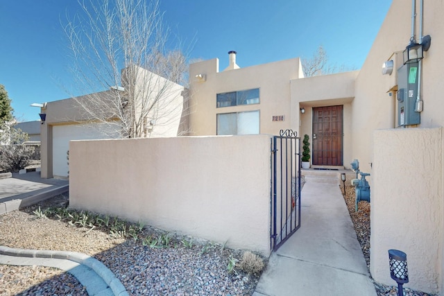 property entrance with a gate, fence, and stucco siding