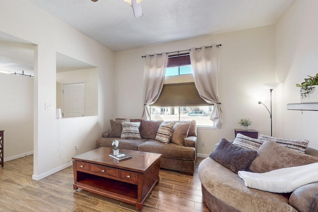 living room with wood finished floors, a ceiling fan, and baseboards