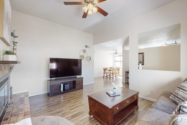 living room featuring visible vents, a fireplace, baseboards, and wood finished floors