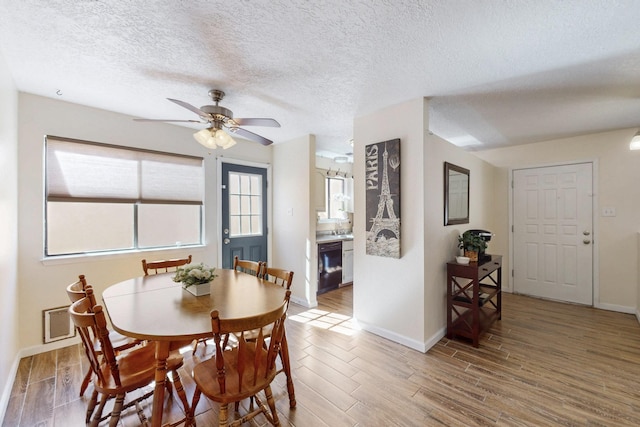 dining space featuring baseboards, a textured ceiling, a ceiling fan, and light wood-style floors