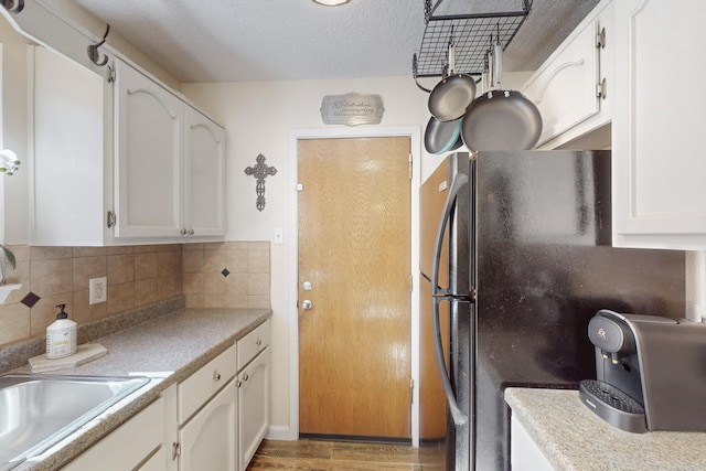 kitchen featuring a sink, white cabinetry, light wood-style floors, freestanding refrigerator, and tasteful backsplash