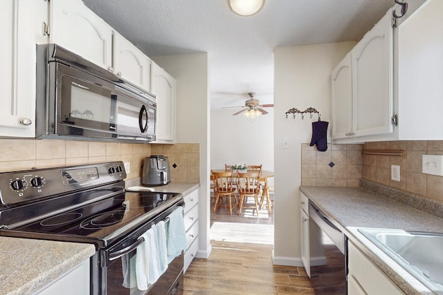 kitchen with black appliances, light wood-style flooring, and white cabinetry