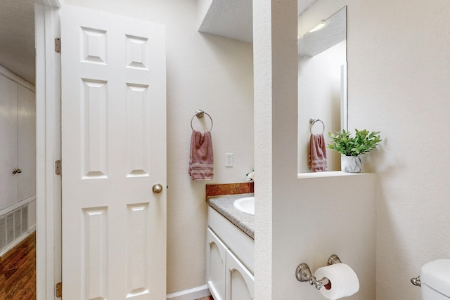 bathroom with visible vents, toilet, wood finished floors, and vanity