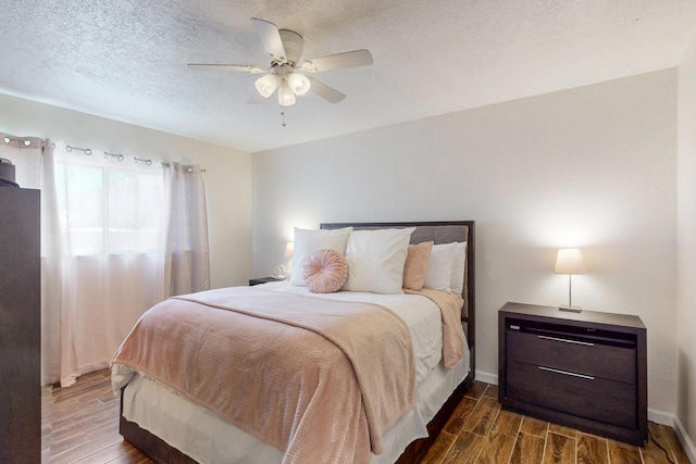 bedroom with wood tiled floor, ceiling fan, a textured ceiling, and baseboards