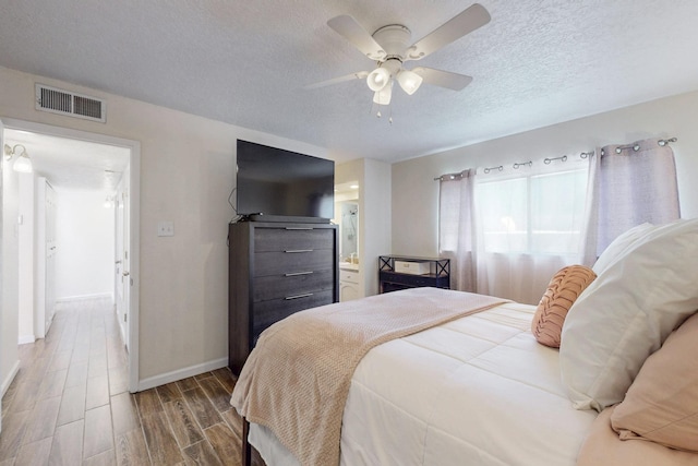 bedroom featuring a textured ceiling, wood finished floors, a ceiling fan, visible vents, and baseboards