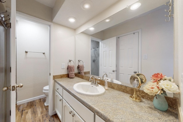 bathroom featuring toilet, recessed lighting, wood finished floors, and vanity