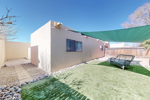 view of home's exterior with a fenced backyard, a lawn, and stucco siding