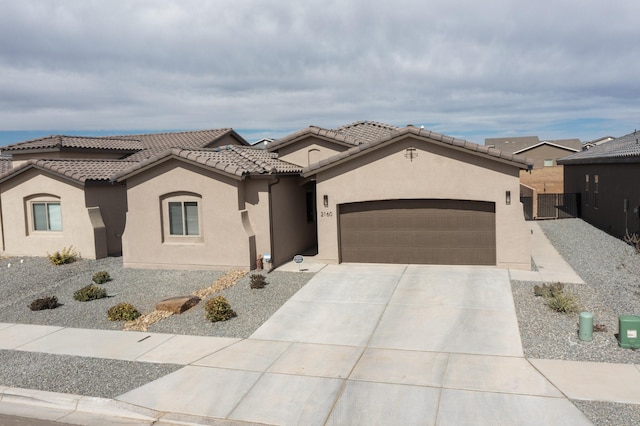 mediterranean / spanish house with a tile roof, a garage, driveway, and stucco siding