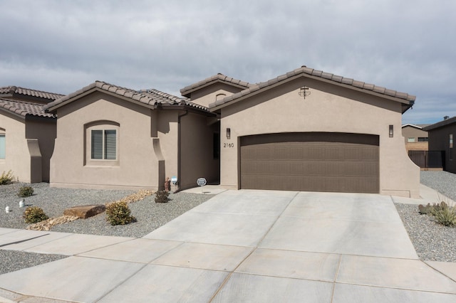 mediterranean / spanish home featuring concrete driveway, an attached garage, a tile roof, and stucco siding