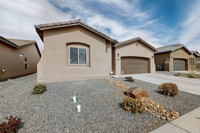 mediterranean / spanish-style house with stucco siding, a tiled roof, concrete driveway, and an attached garage