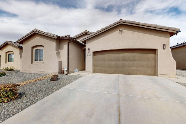 mediterranean / spanish house with stucco siding, driveway, a tile roof, and a garage