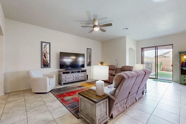 living room featuring ceiling fan, arched walkways, visible vents, and light tile patterned floors