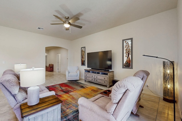 living room with tile patterned floors, a ceiling fan, visible vents, and arched walkways